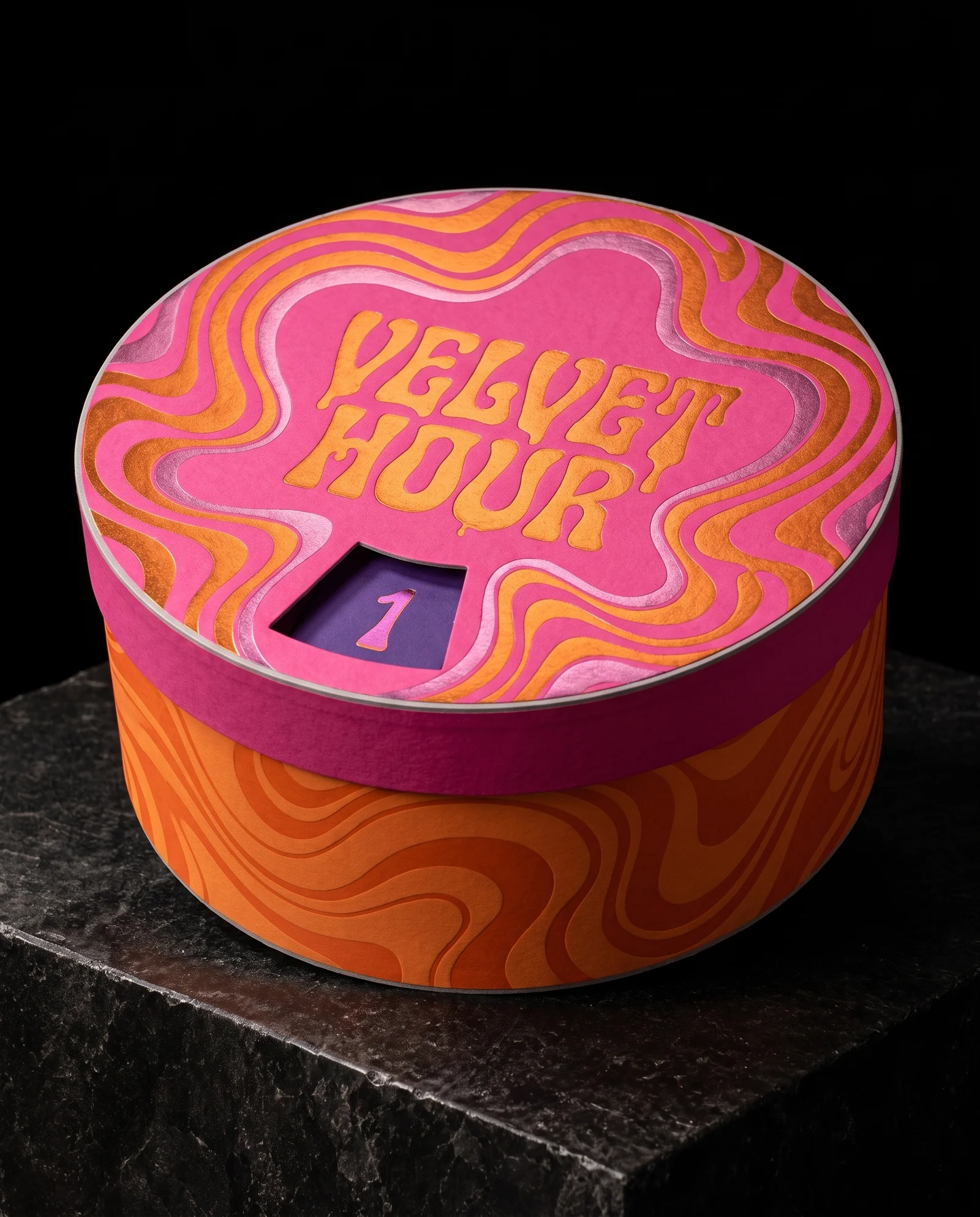 A round hot pink and tangerine hatbox advent calendar with swirling metallic orange-gold and pink foil, VELVET HOUR in melting psychedelic lettering, and a die-cut window in the lid showing a purple compartment numbered 1.