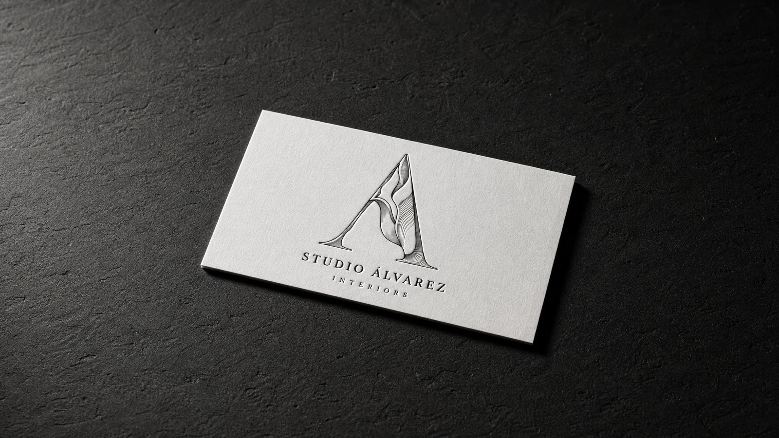 The finished Studio Álvarez Interiors card lying on warm bone, the stone A printed in a single ink