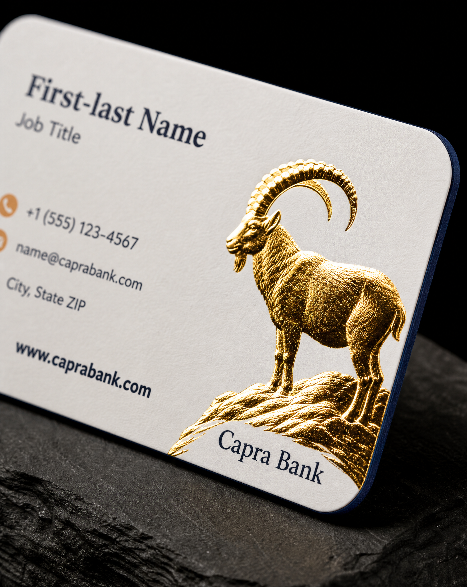 Close detail of the Capra Bank business cards — 3.375 × 2.125 in, rounded corners, 32pt soft-touch matte, Gold hot foil, both sides, PMS 654 C + PMS 728 C spot, Painted edge, PMS 654 C.