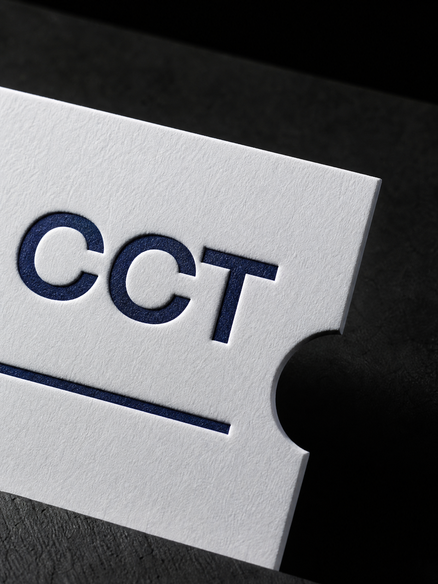 Macro: the navy letterpress CCT and the clean die-cut notch edge in the cotton