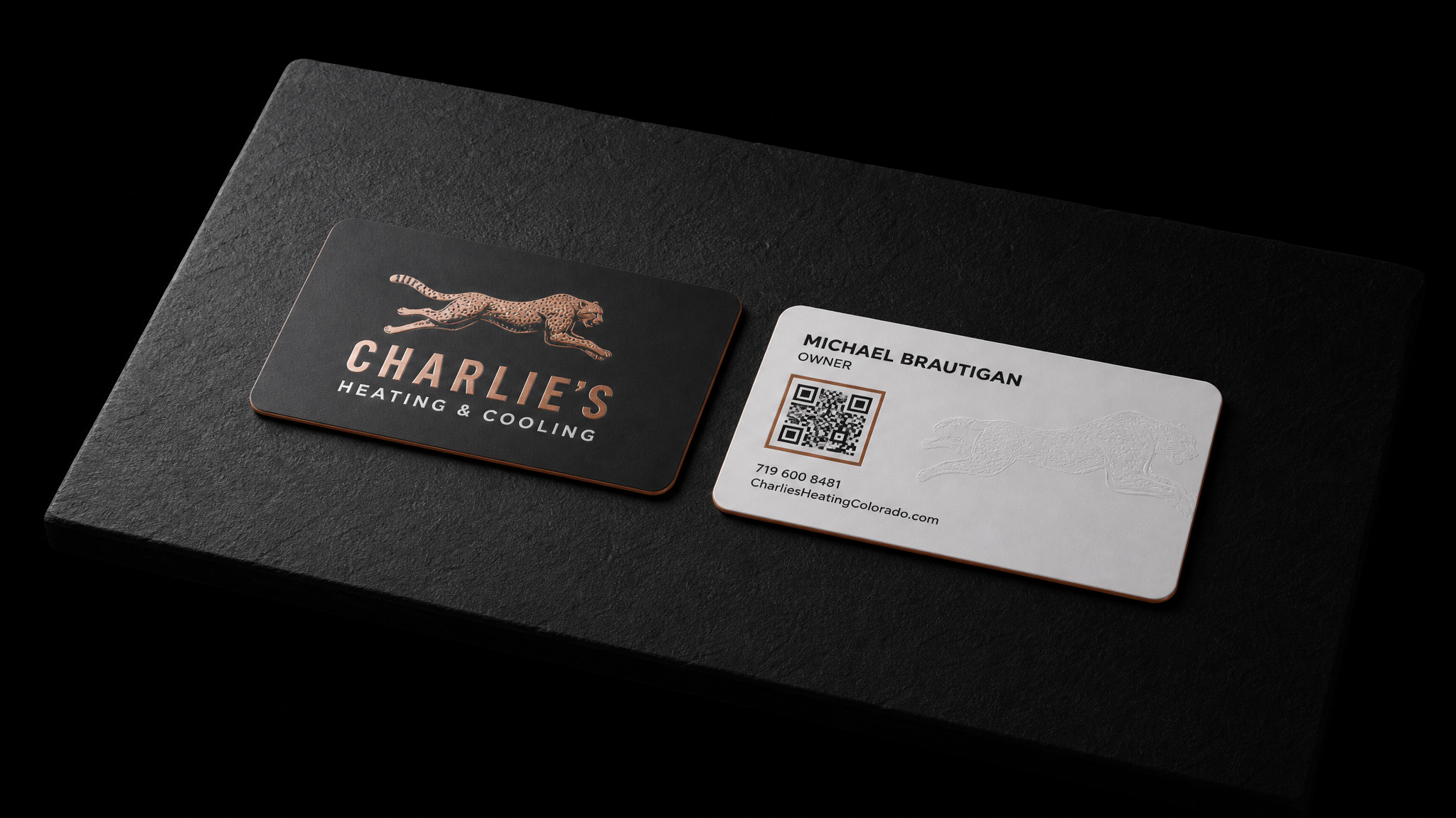 The finished Charlie's Heating & Cooling business cards shown in full — 3.5 × 2 in, rounded corners, 16pt soft-touch laminate, charcoal / white duplex face, Copper hot foil, White ink, Blind emboss (reverse ghost), Painted edge, copper.