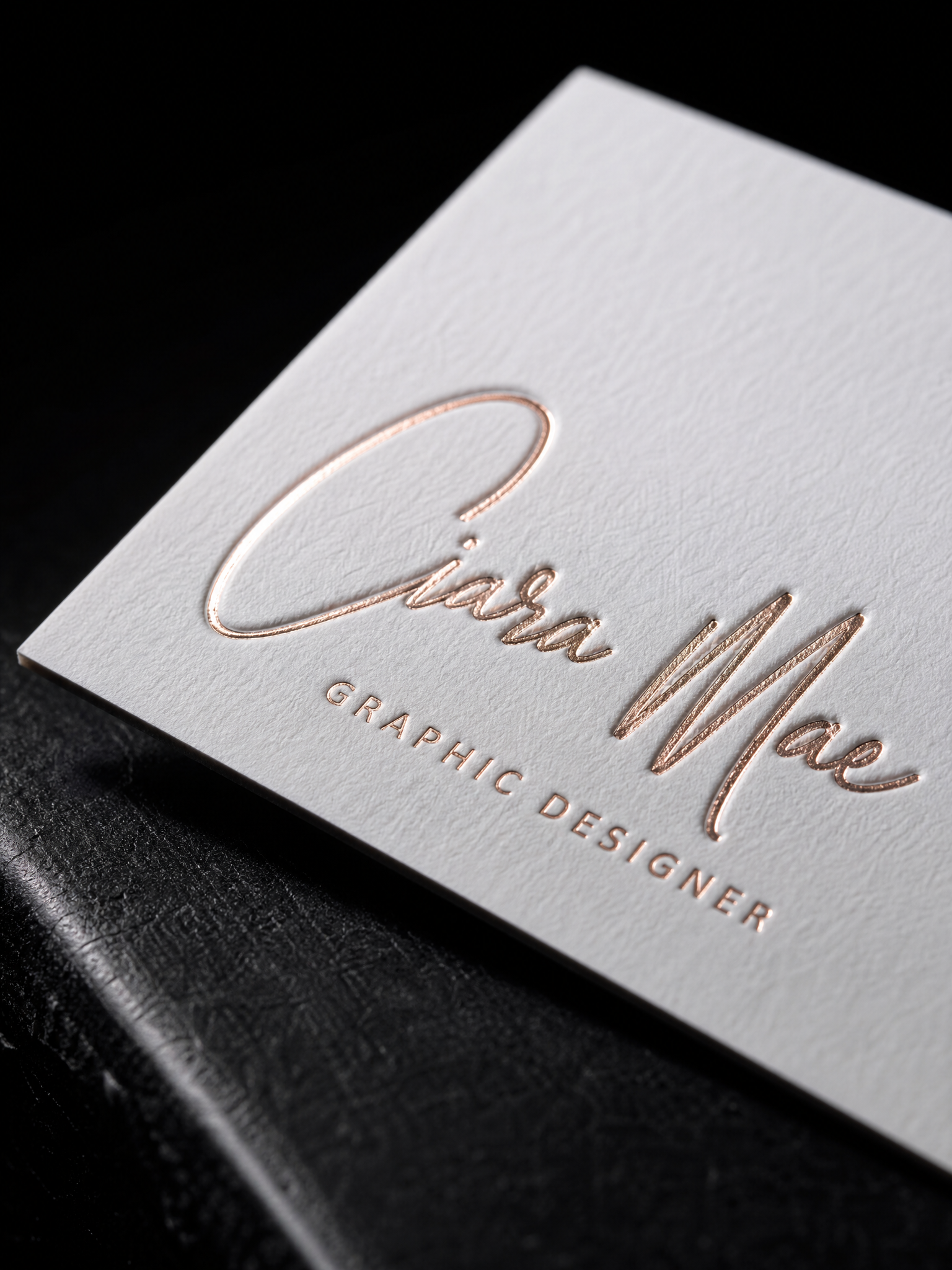 Macro: the rose gold foil script sitting in its deboss, the cotton tooth around it