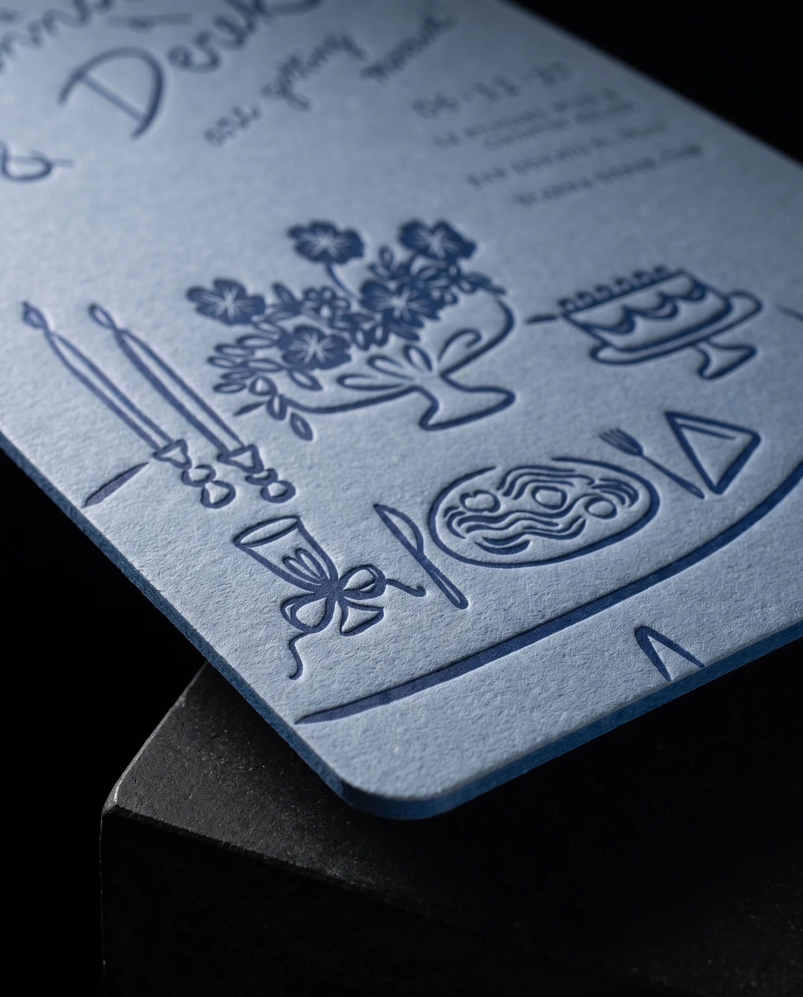 Close simulated view of the navy table illustration pressed into dusty-blue invitation stock