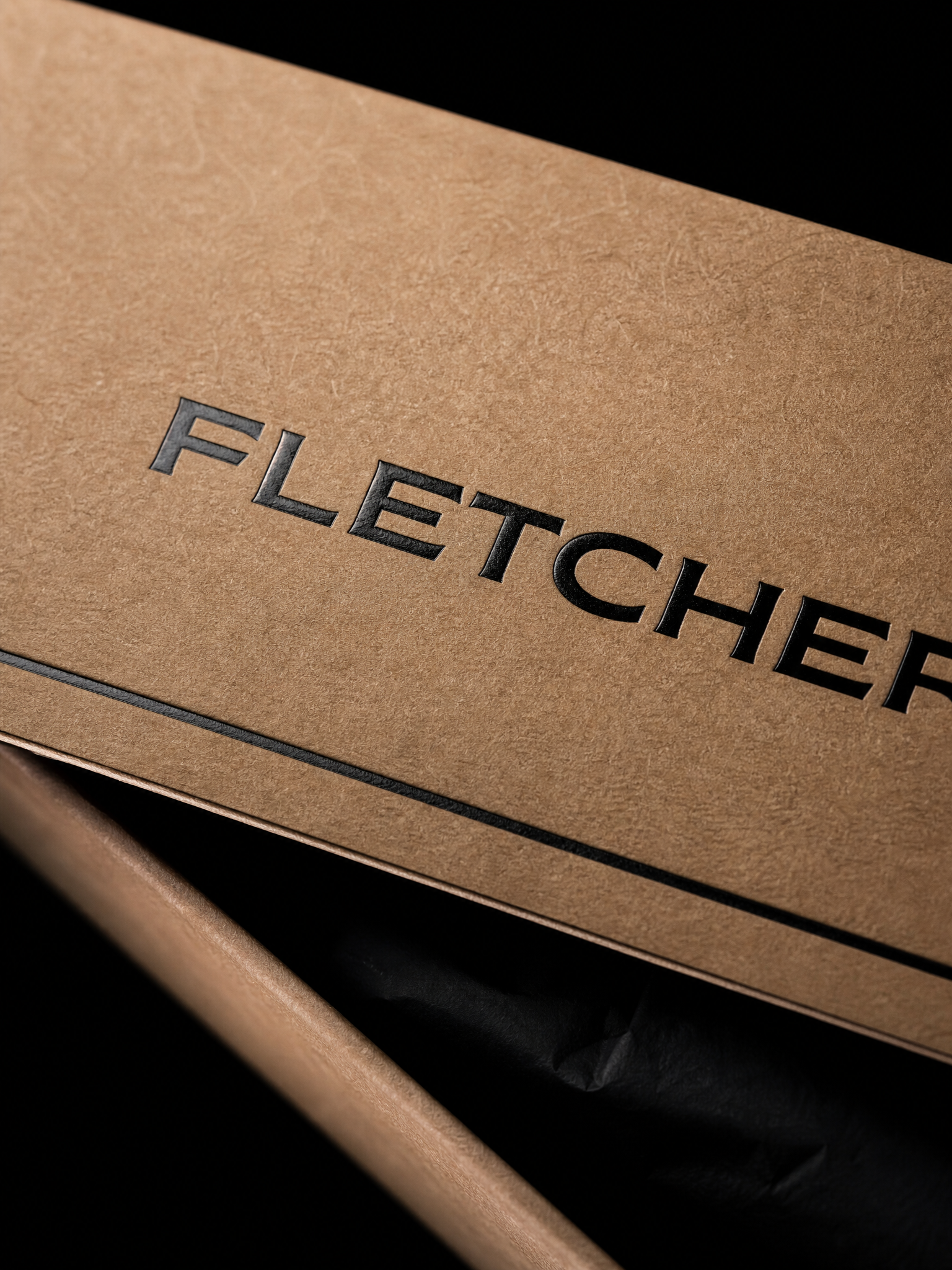 Macro: the black foil wordmark pressed into the kraft wrap, kraft fibre around the letters