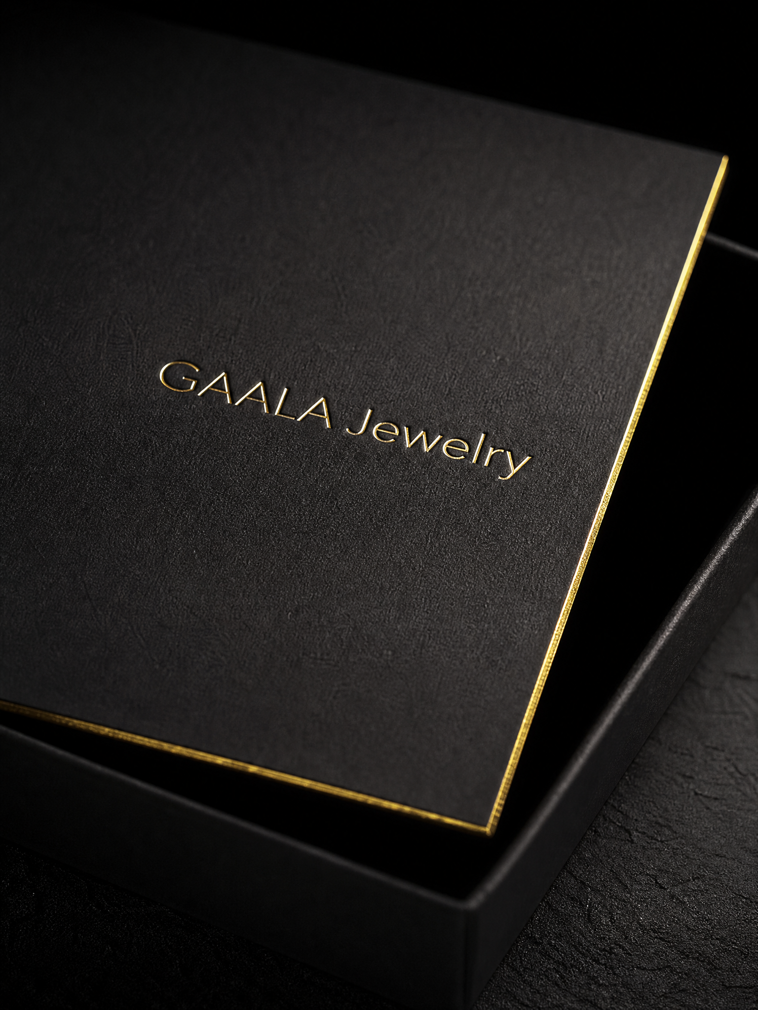 Macro: the gold foil GAALA wordmark recessed into the black cotton, the gilded edge