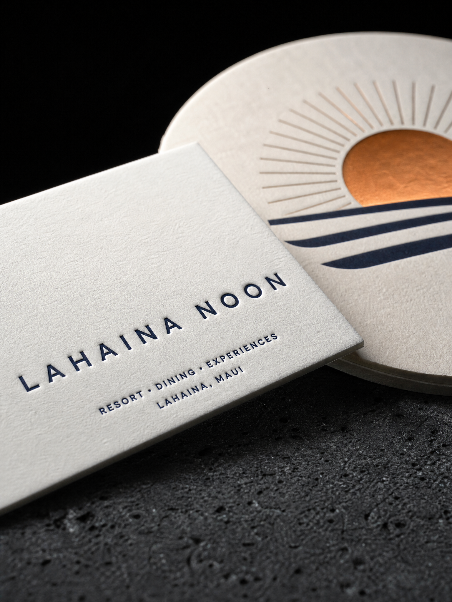 Macro: the navy letterpress caps in the cotton, the absorbent coaster board edge