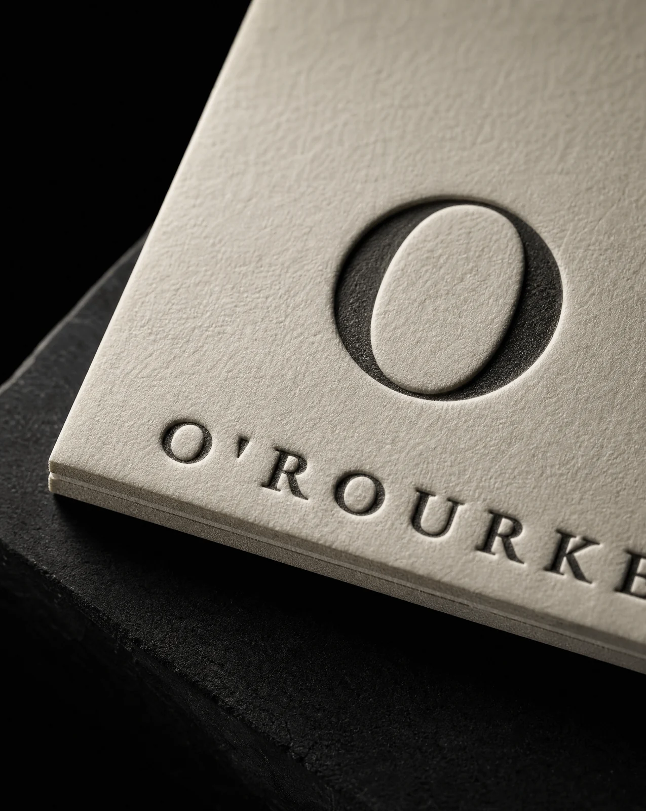 Macro of the O'Rourke monogram and wordmark bitten into duplexed cotton in a single black letterpress pass