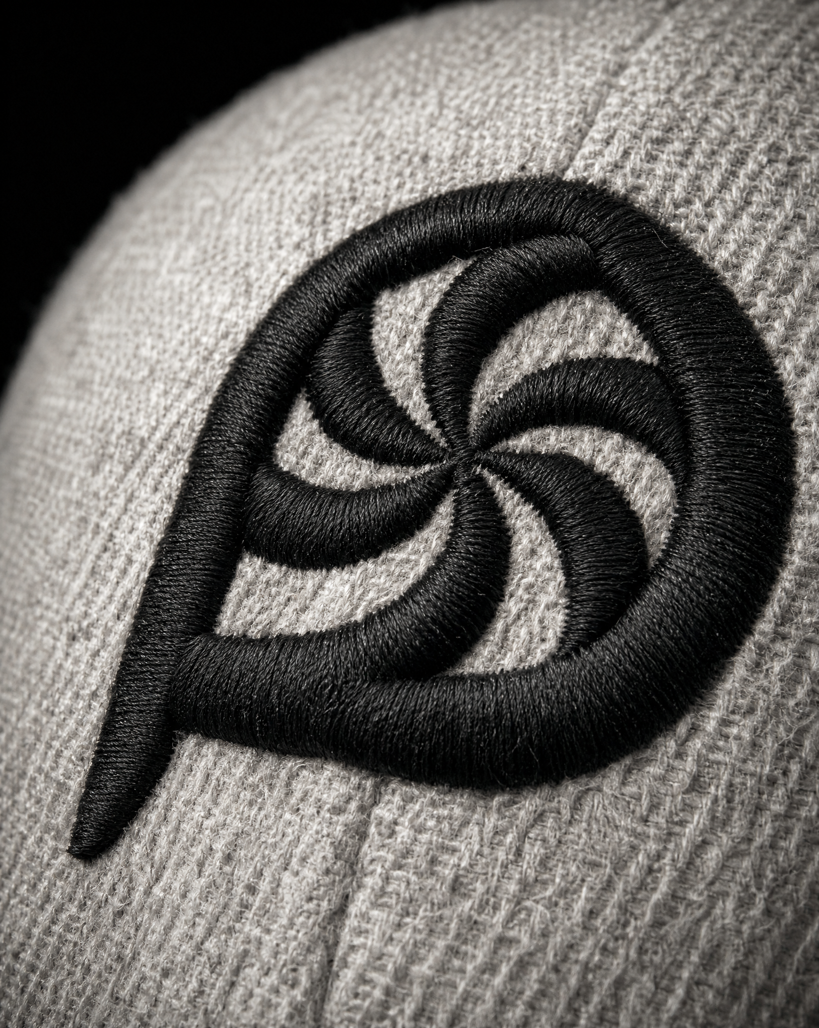 Macro of 3D puff satin stitch embroidery on heather grey cap fabric