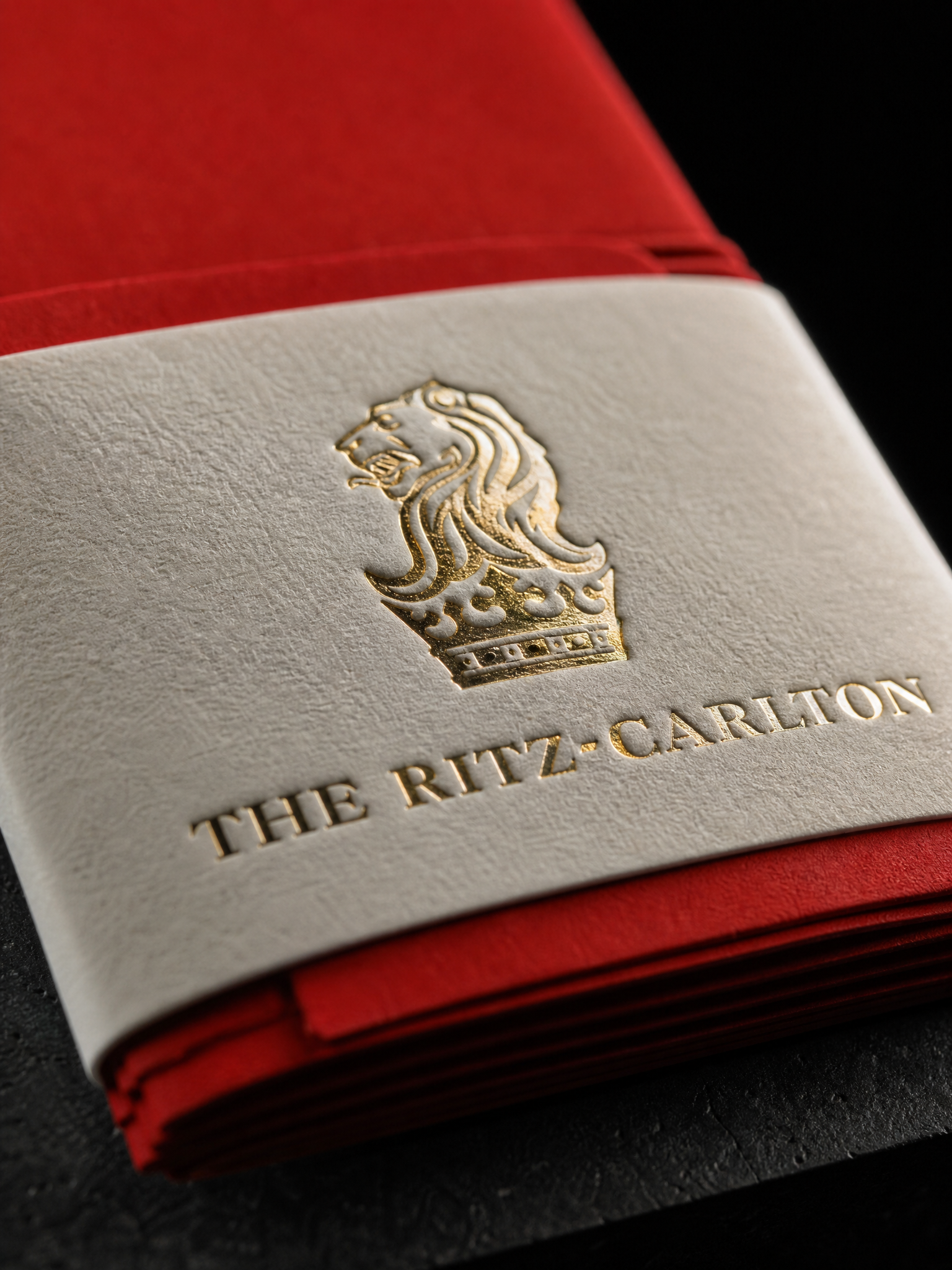 Macro of the gold crest on cream cotton band against red envelopes