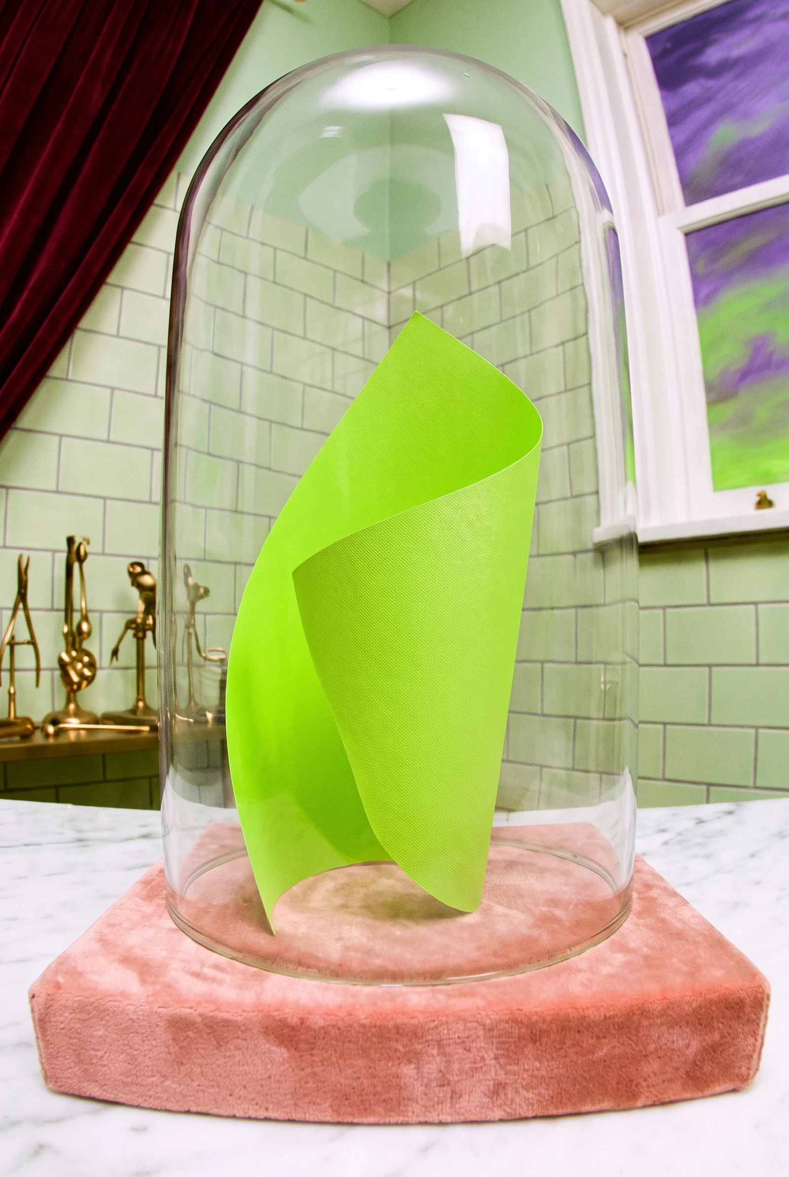A curled sheet of neon green paper under a glass bell jar