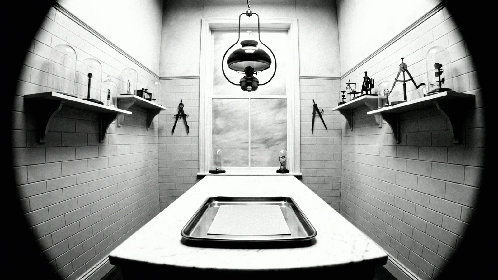 Black-and-white wide of the anatomy study, an empty tray under the lamp
