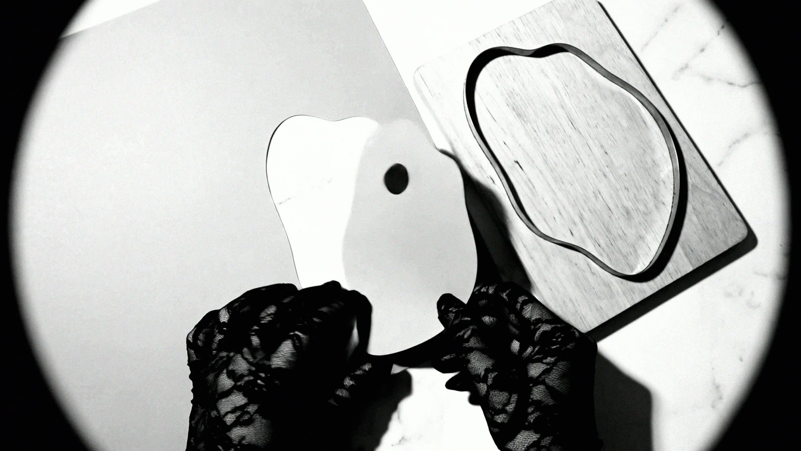 Lace-gloved hands lift the cut card away from the die