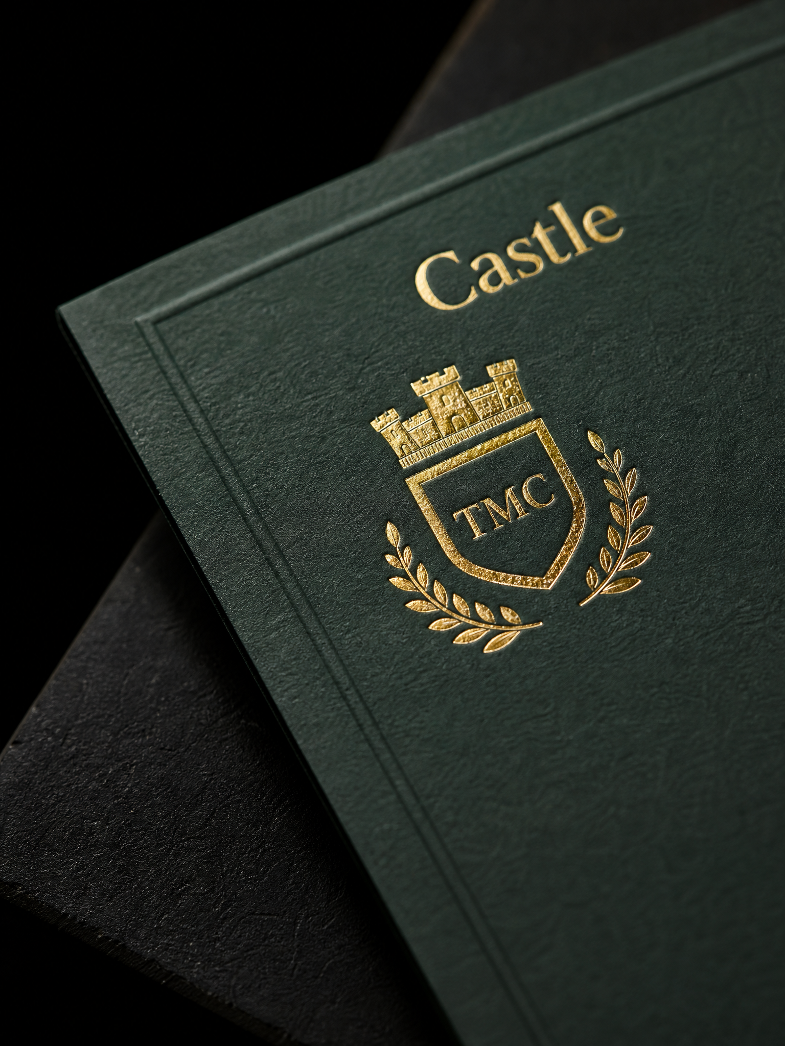 Macro: the gold foil crest on the Castle tier against its forest flood, silk surface