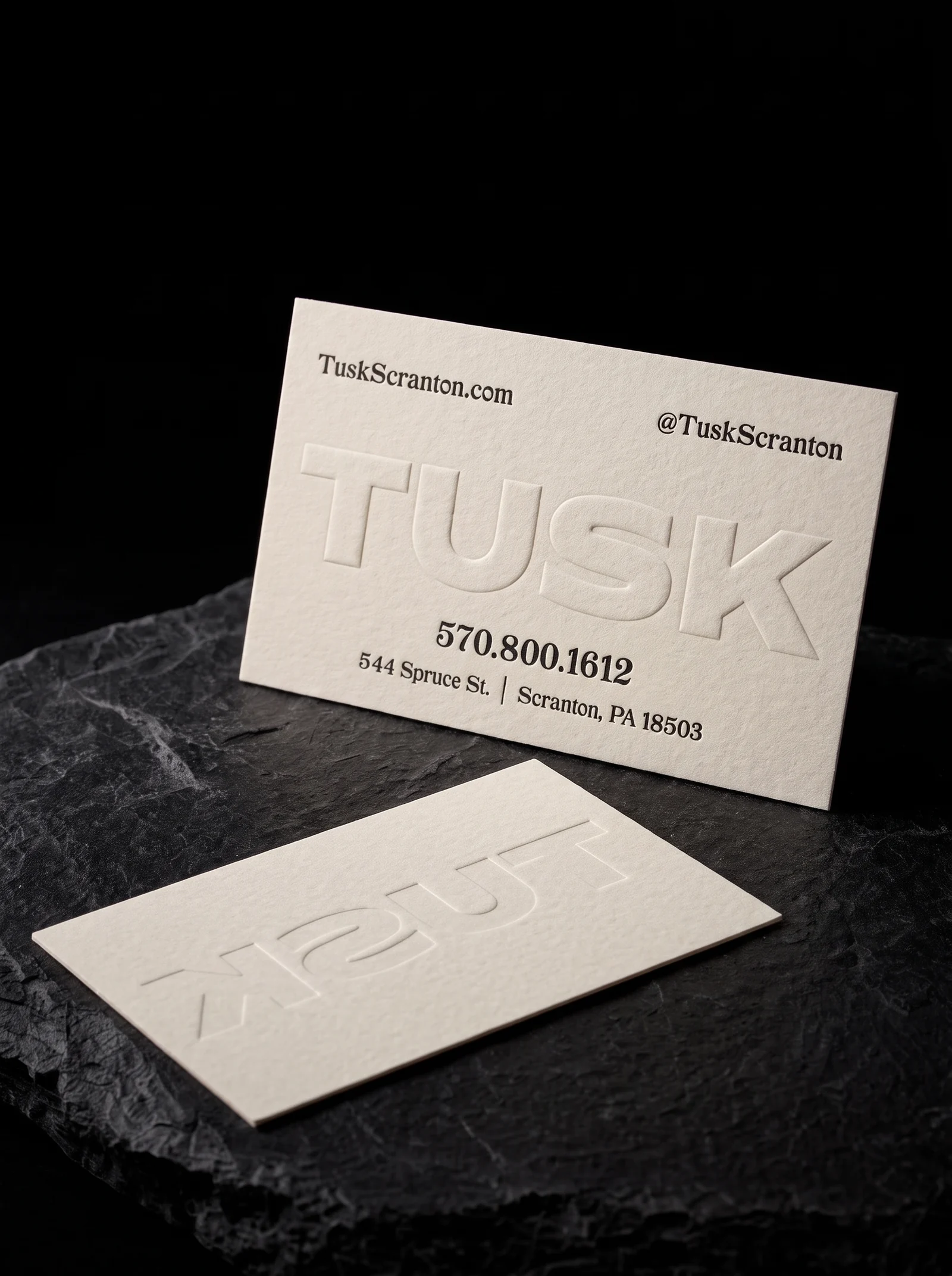 Off-white cotton card with a large blind embossed name and small black letterpress type