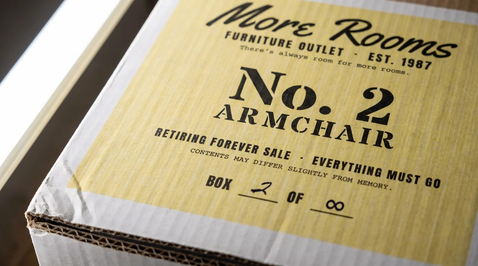 Macro of a printed corrugated box panel: pale yellow flexo flood with faint pinstripes, black script logo, double-wall cut edge