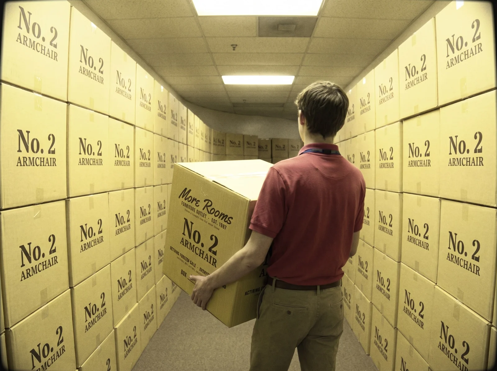 Camcorder frame of a teenage employee carrying a box down a corridor of stacked boxes
