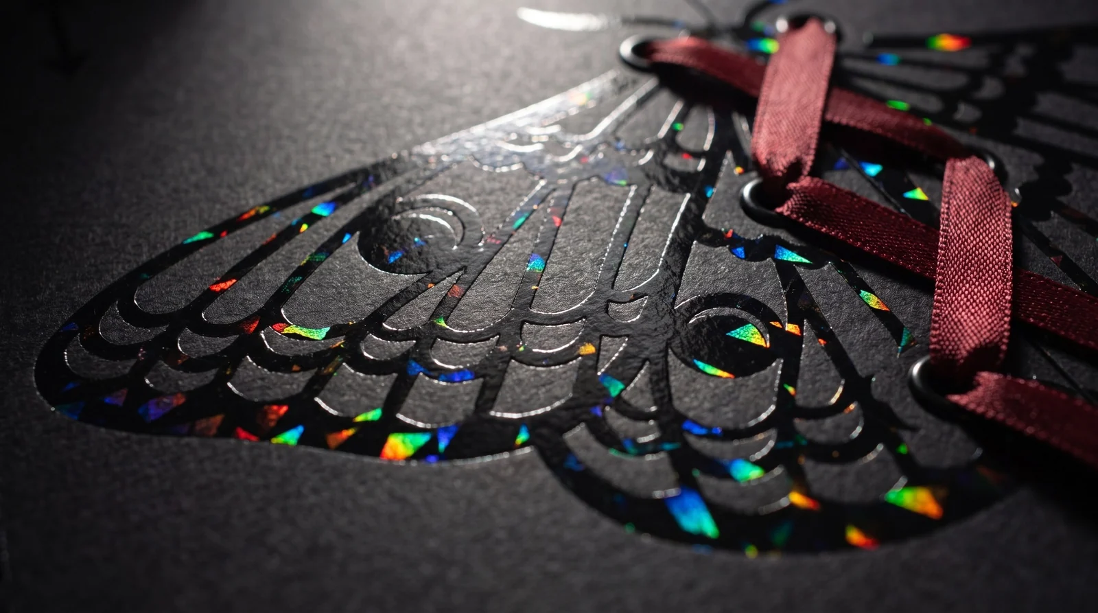 Macro of black holographic gemstone foil flashing rainbow on jet-black paper