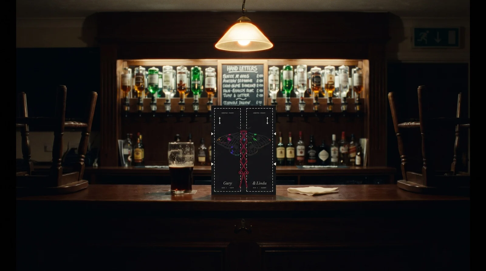 The laced black invitation on an empty bar at night, beside a half-finished pint