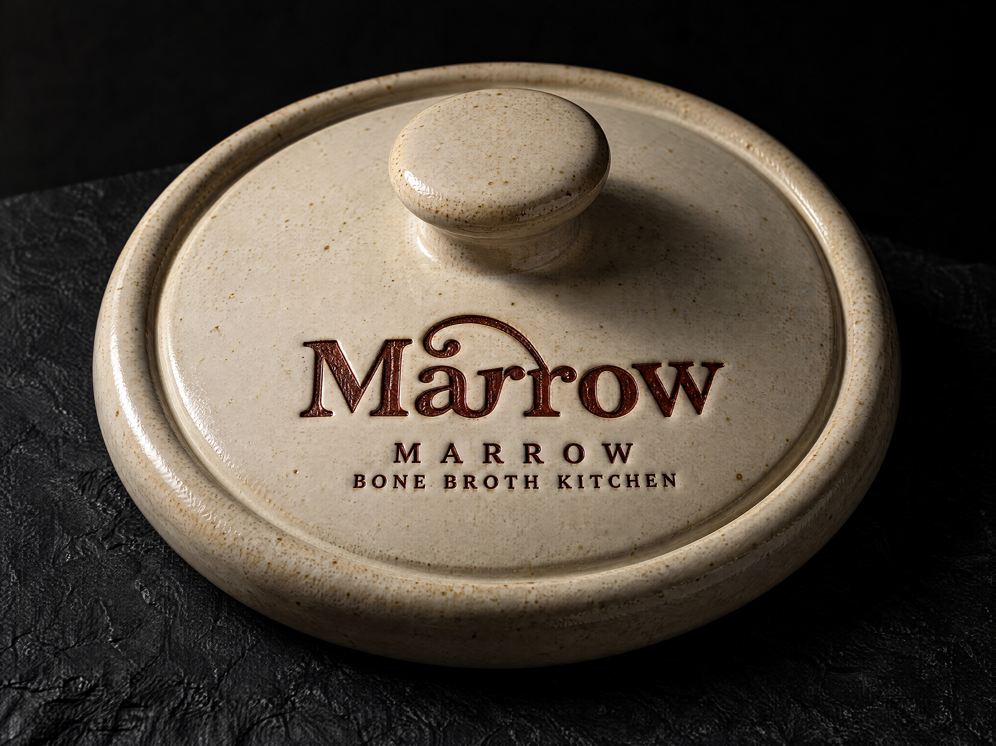 Marrow logo and brand identity for a bone broth and stock kitchen, designed by Print Peppermint, shown as a debossed oxblood glaze stamp in the ceramic