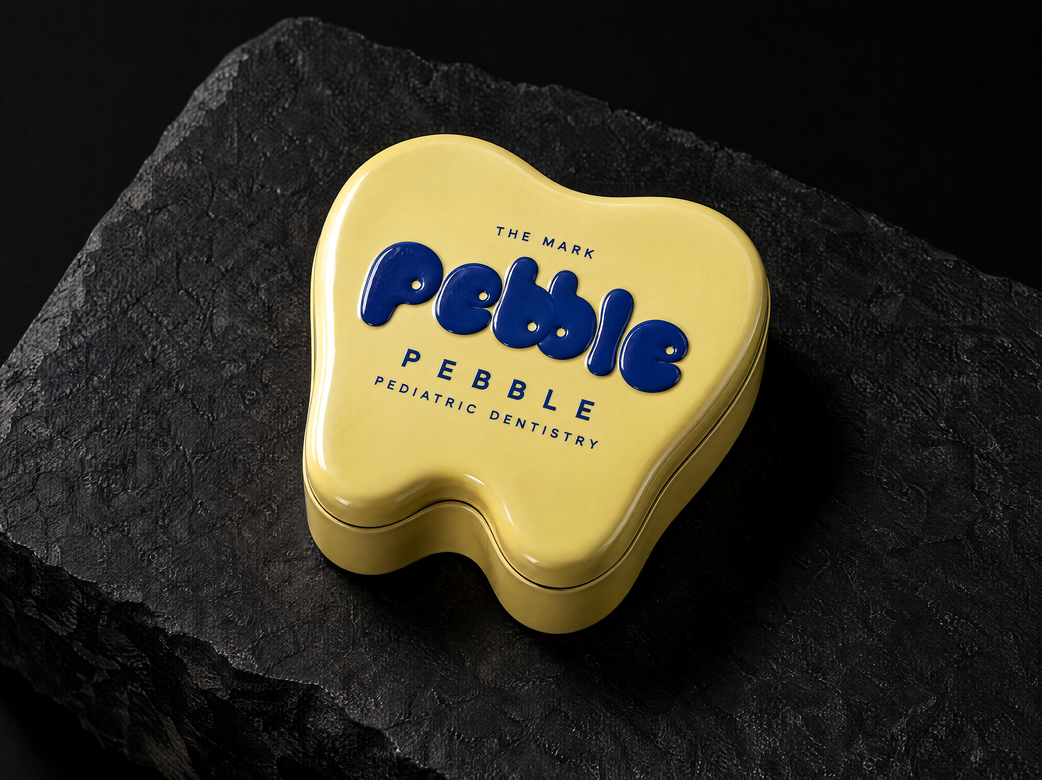 pebble logo and brand identity for a children's dental practice, designed by Print Peppermint, shown as a raised cobalt enamel print on the lid
