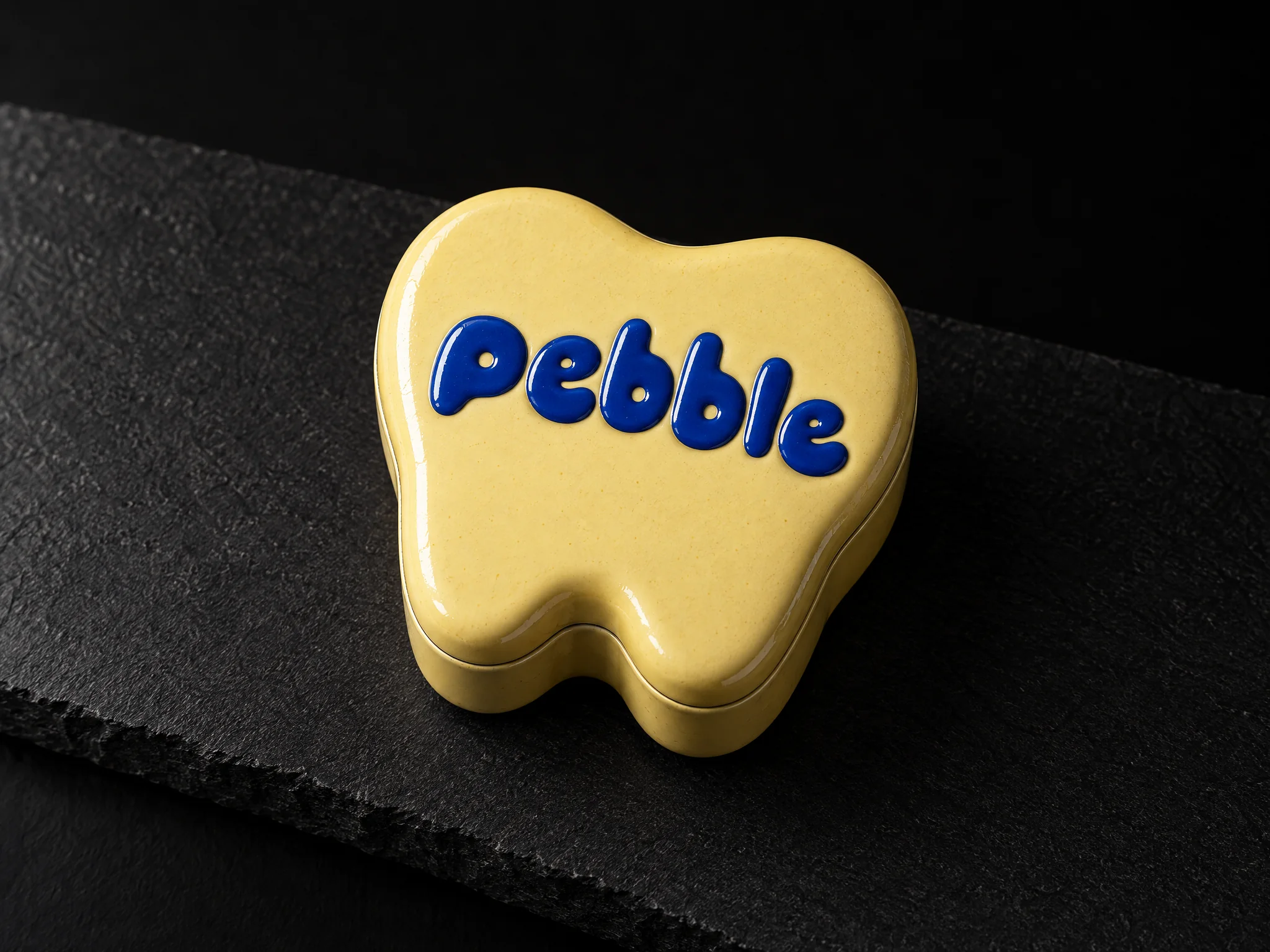 Pebble pediatric dentistry identity, designed by Print Peppermint, printed on a yellow tooth-shaped dental keepsake