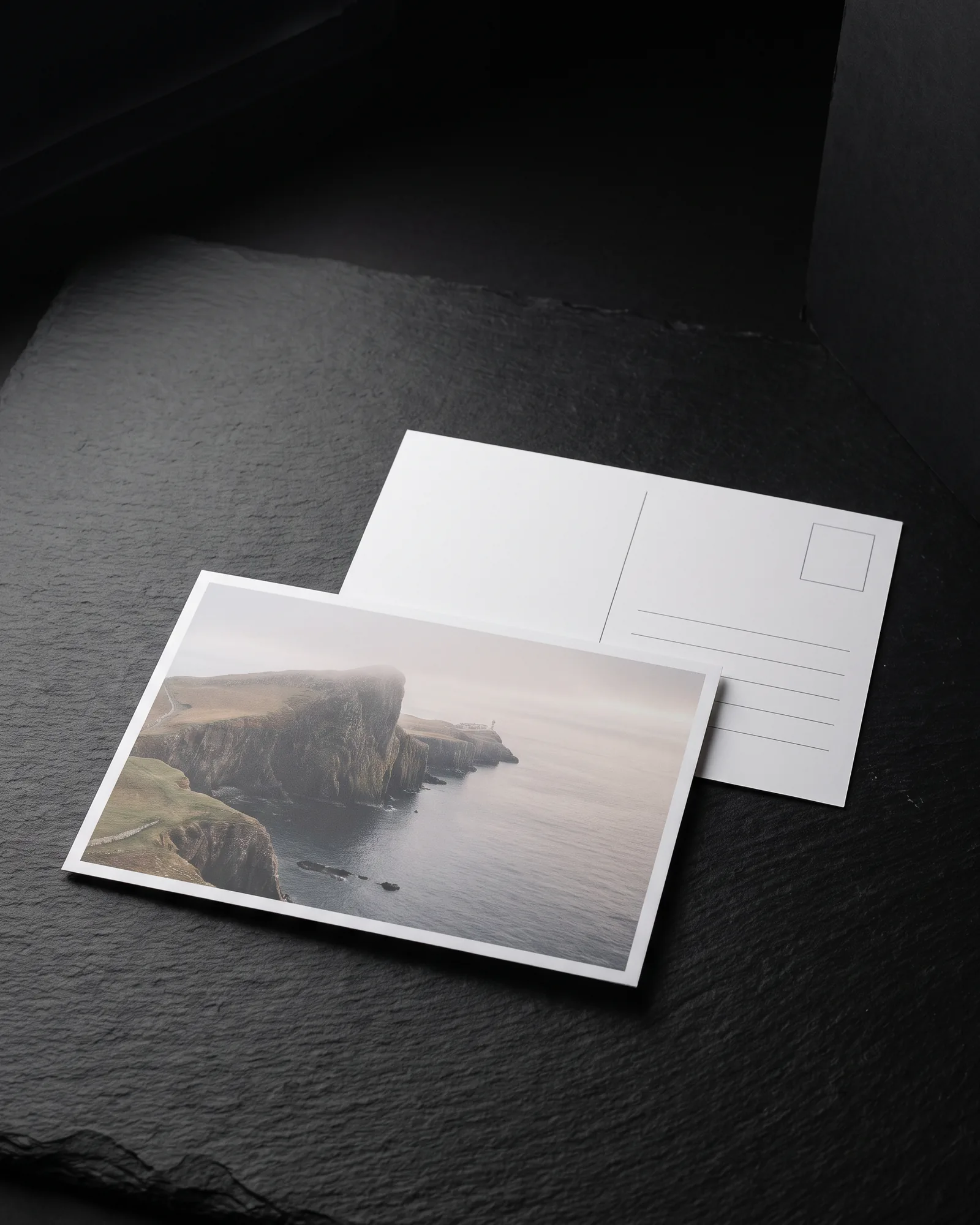 Two 4x6 matte postcards on black slate: the front shows a misty coastal cliff photo with no glare, the second shows a printed back with a stamp box and address lines