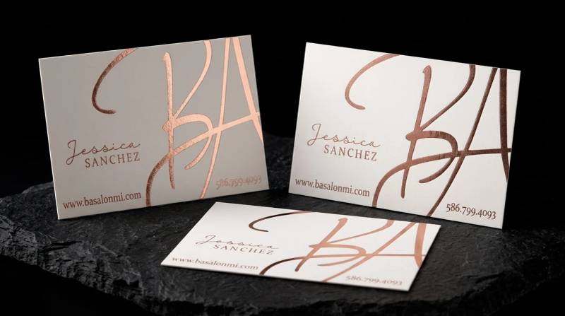 BA Salon Collective business card: Mirror rose-gold foil monogram on warm white, running off two edges