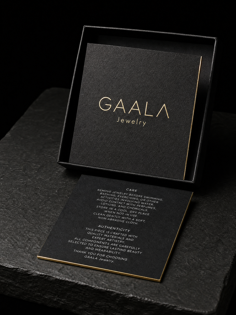 Square black cotton insert card with a gold foil wordmark and gold gilded edges.