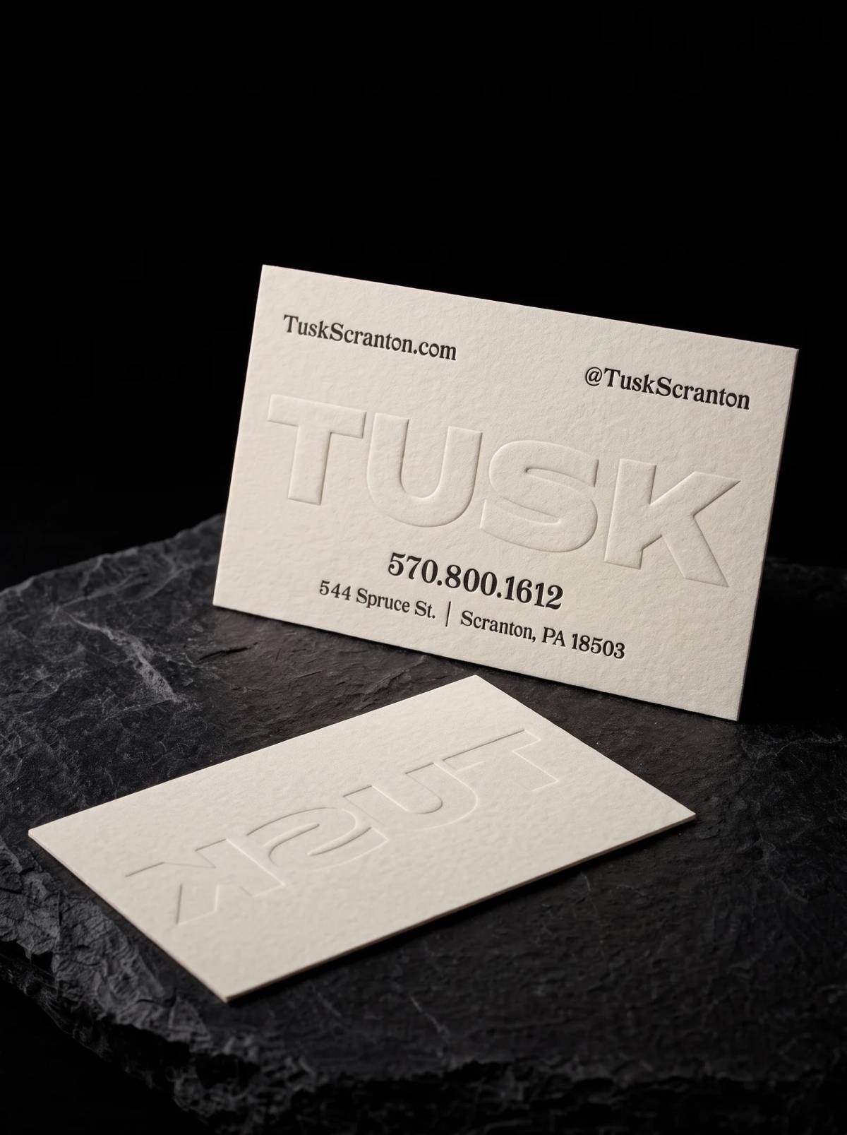 Off-white cotton card with a large blind embossed name and small black letterpress type