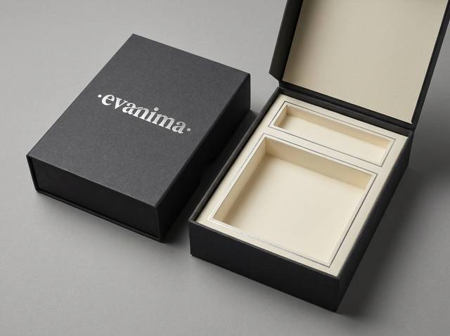The Satin Reveal concept: Charcoal uncoated matte (exterior); warm ivory uncoated matte (interior) · Satin silver foil logo · Satin silver foil compartment divider lines